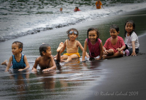 Lembeh Strait-Local kids playing on black sand beach. by Richard Goluch 